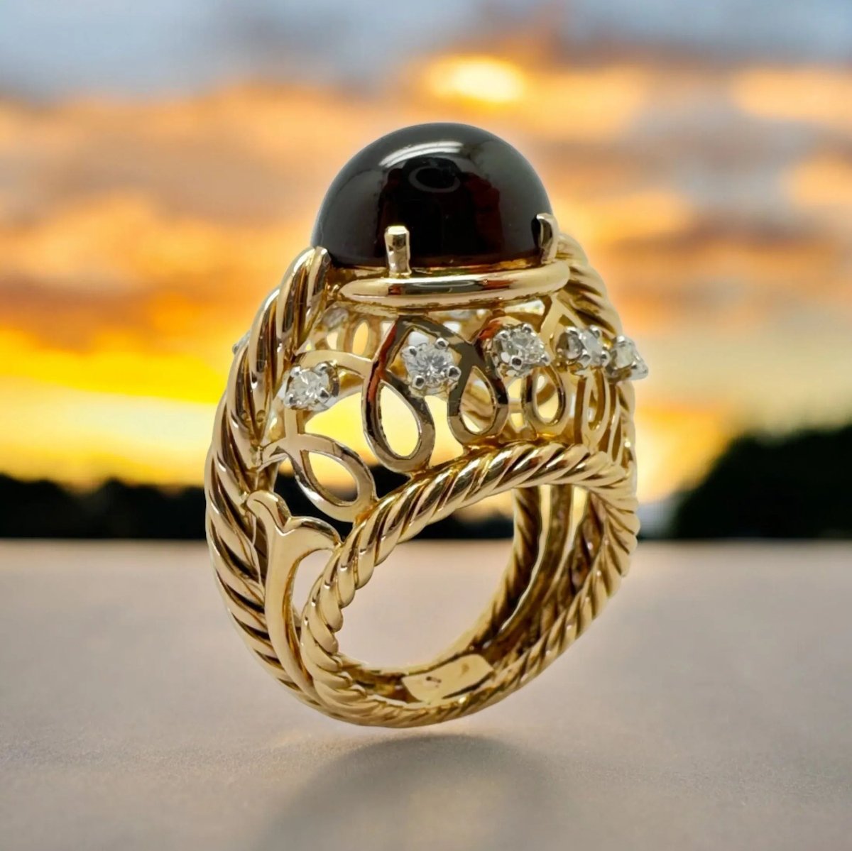 Bague dôme en or jaune ornée d’un grenat entouré de diamants. - Castafiore