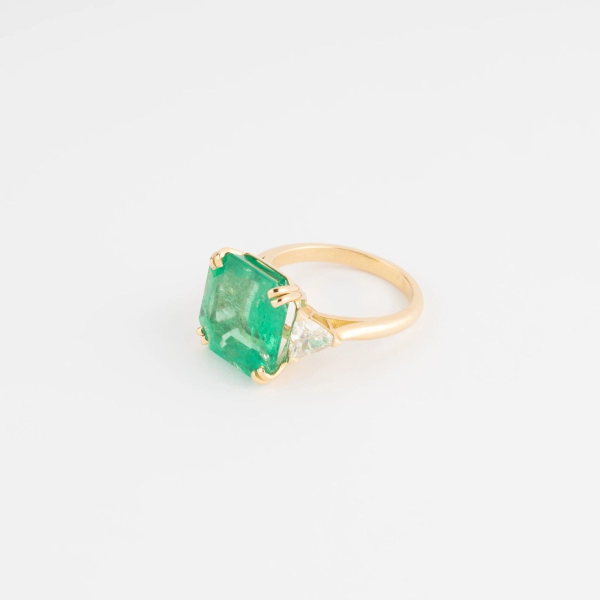 Bague en or jaune ornée d'une émeraude taille émeraude épaulé de diamants triangles - Castafiore