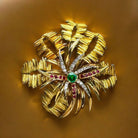 MELLERIO Broche en or jaune, le centre orné d’émeraude, de rubis et de diamants. - Castafiore